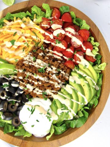 overhead view of Keto Taco Salad in wooden bowl with dressing drizzled on top